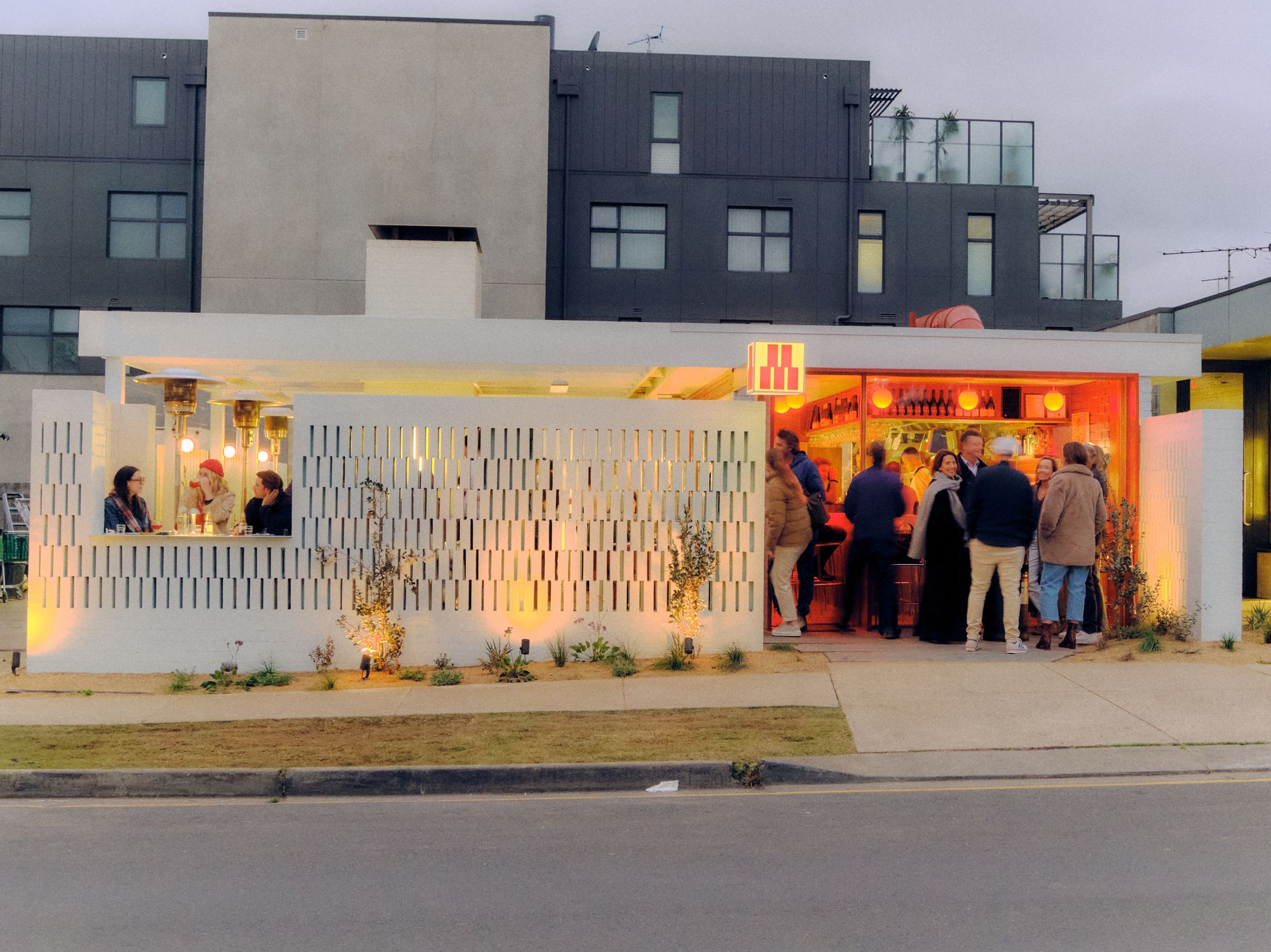 MULE at dusk, the crowd gathered at the glowing bar behind the breeze-block wall